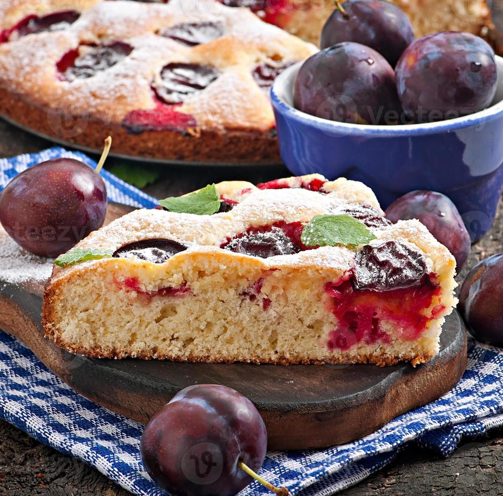 Delicious homemade cake with plums on a wooden background photo