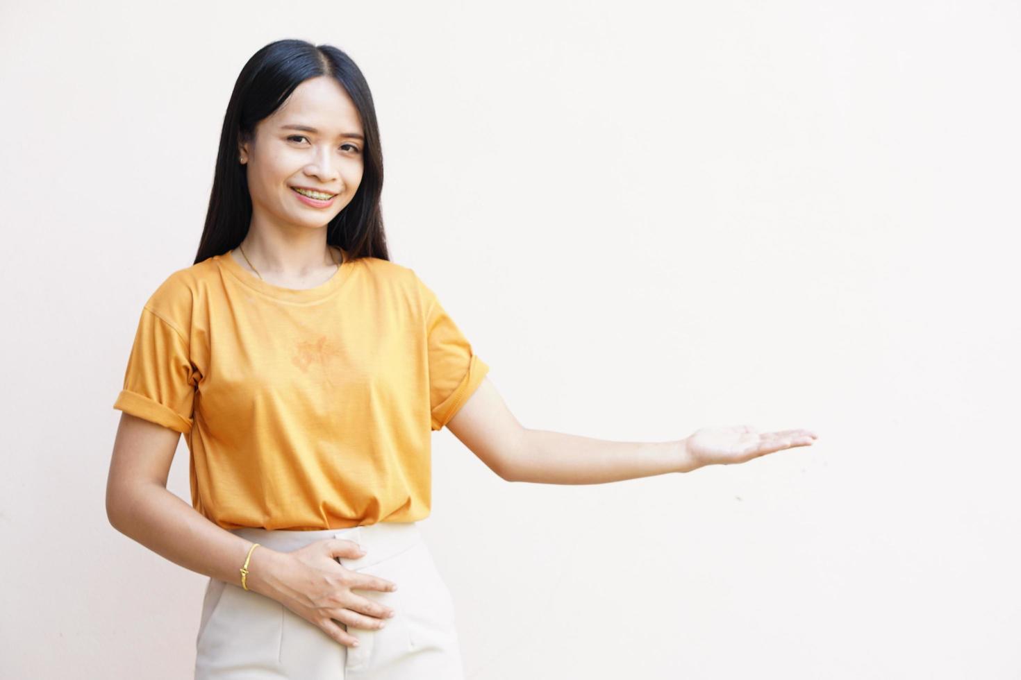 Young woman over isolated gray background holding fantasy copyspace on palm to insert ad. photo