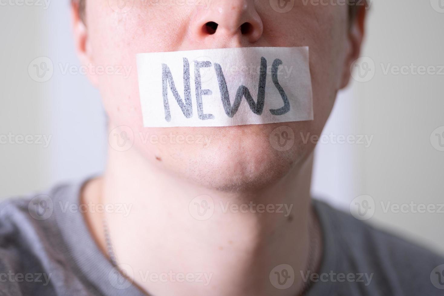 A man gags his mouth with duct tape that reads the news. photo