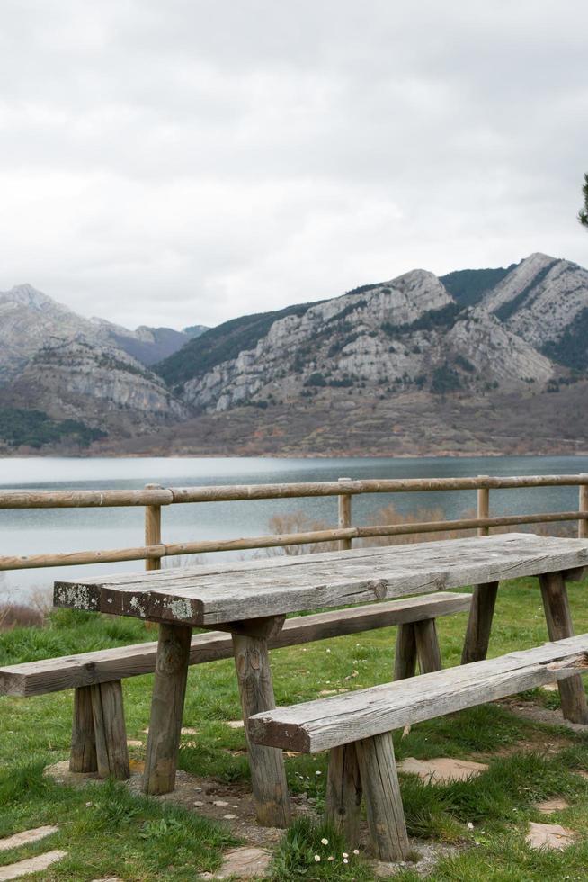 Picnic area with wooden table and bench. Magnificent view of the water reservoir at Caldas de Luna and the mountains around. Spain photo