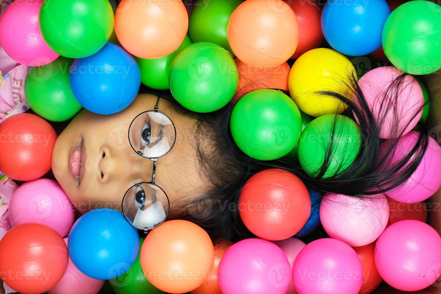 Closeup of flat face little girl on colorful ball background photo