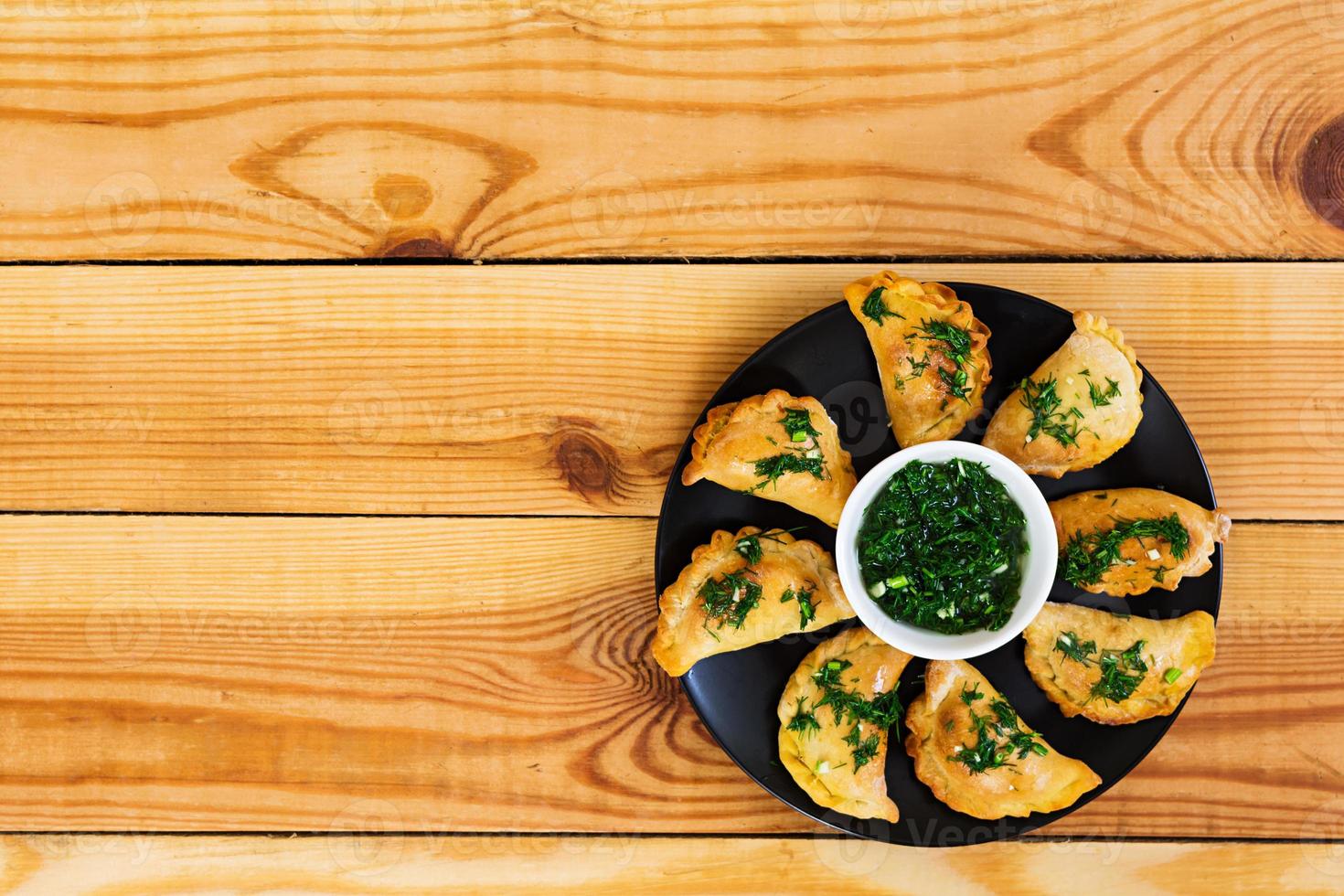 Baked dumplings with dill sauce. Top view photo
