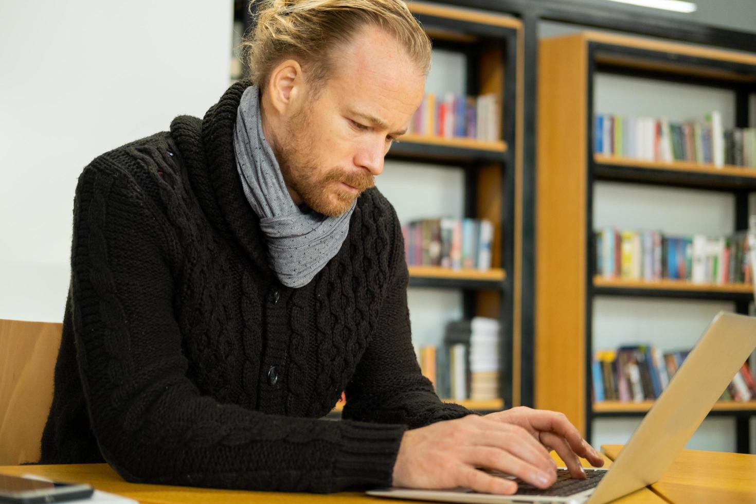 Handsome male read book and work in modern library photo
