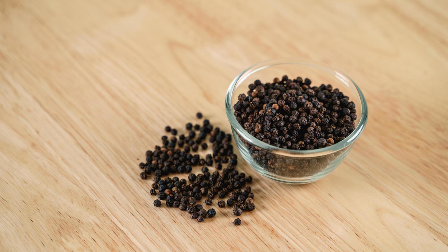 Black pepper in a glass bowl on the wooden table. food, spice, seasoning Concept. photo