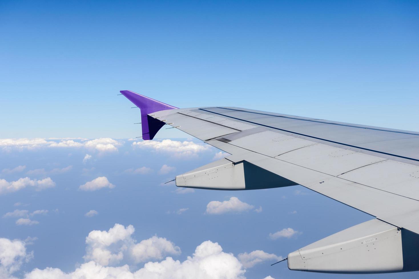 Wing of the plane flying above the clouds. View from the window of an airplane photo