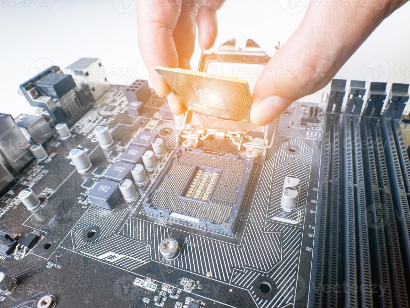 Hold the CPU handle and insert it into the CPU slot on the motherboard. It's an old motherboard, lots of dust. Put orange light on the cpu slot. There is a RAM slot next to it. There is a capacitor. photo