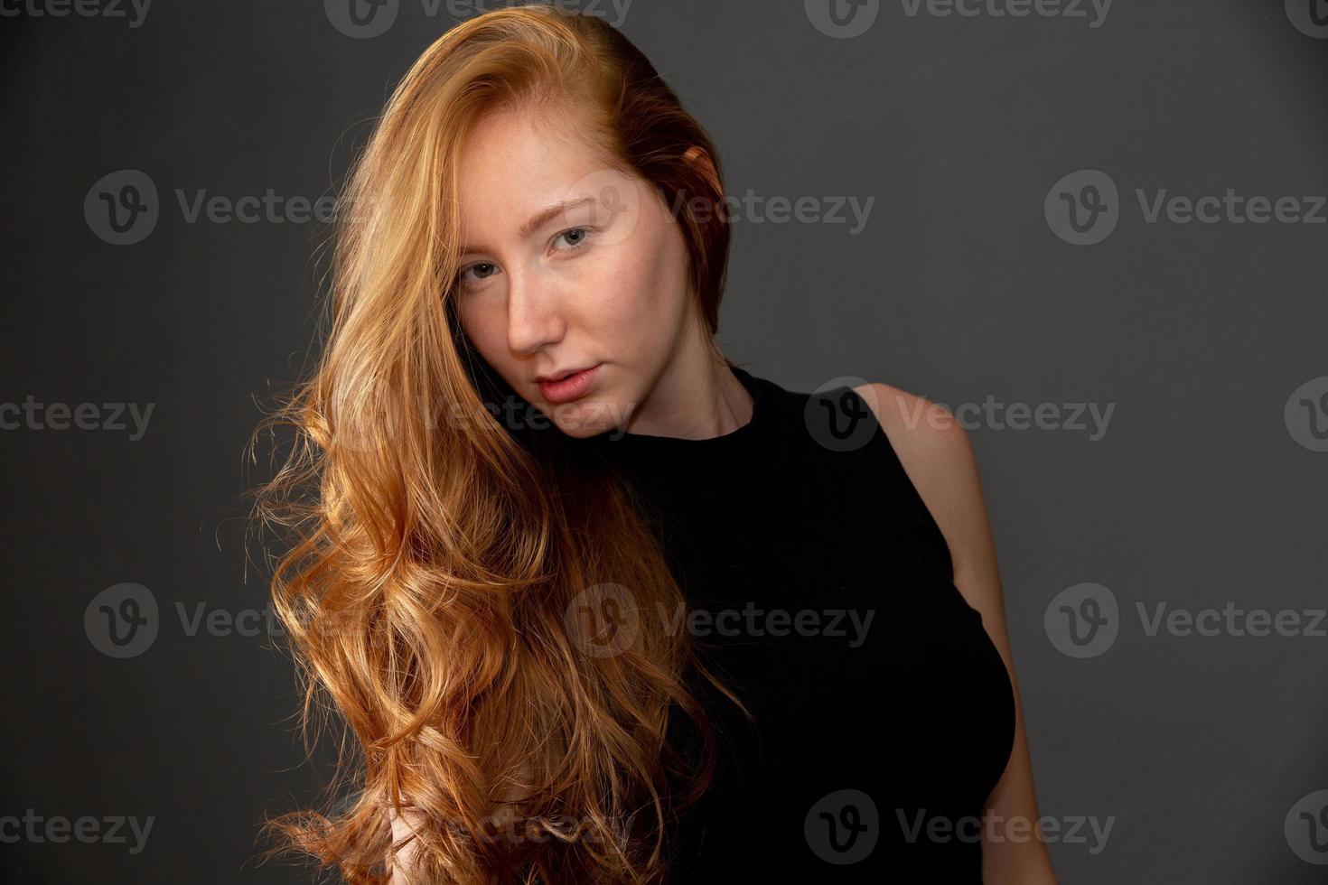 Portrait of beautiful cheerful redhead girl smiling laughing looking at camera over black background. photo