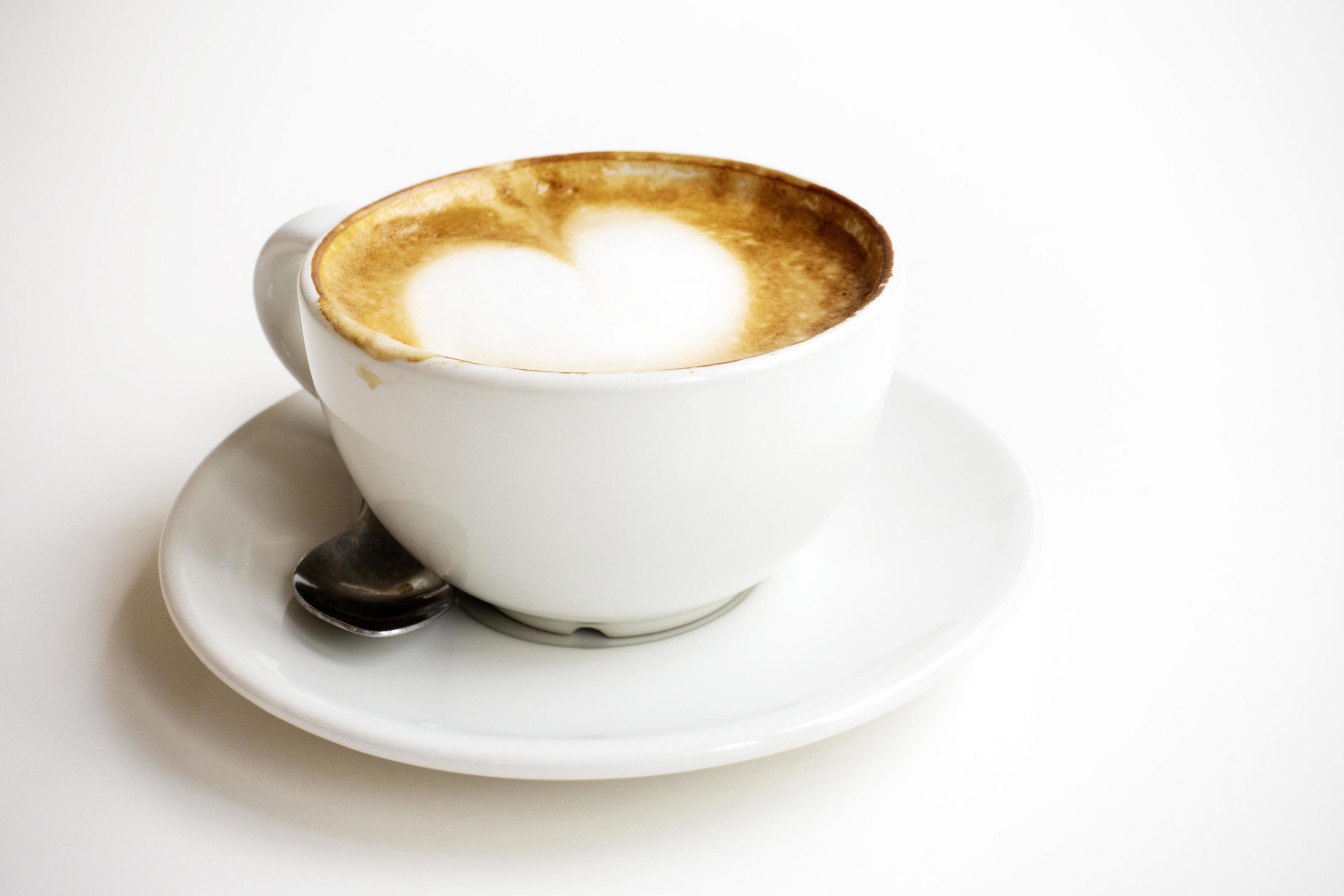 Hot latte With art milk froth in a coffee cup on a white table