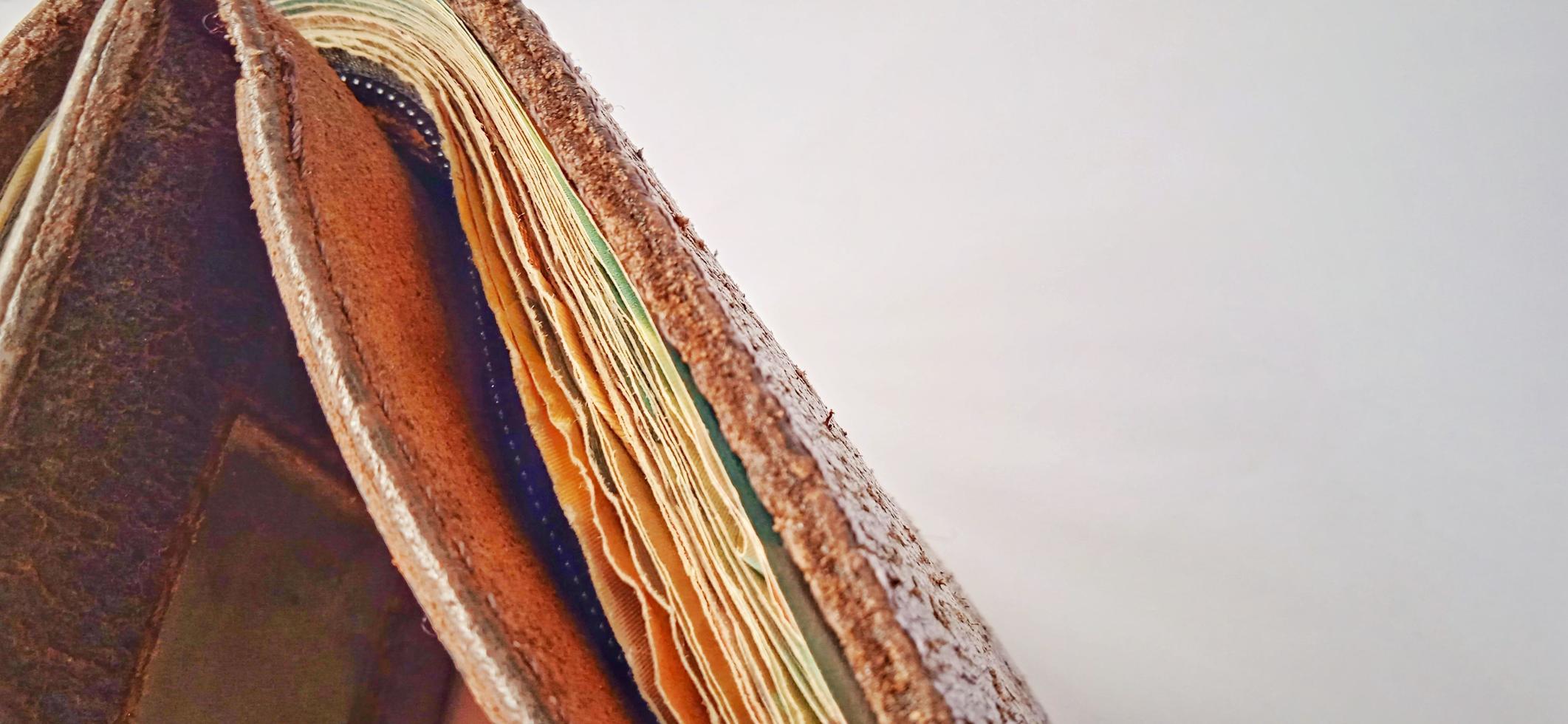 An old brown orange synthetic wallet with some money inside on the dim grey yellow background. photo