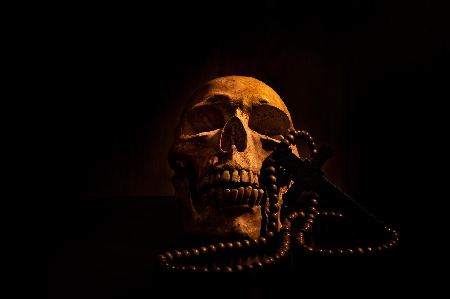 Still life art of a human skull and bead on a black background photo