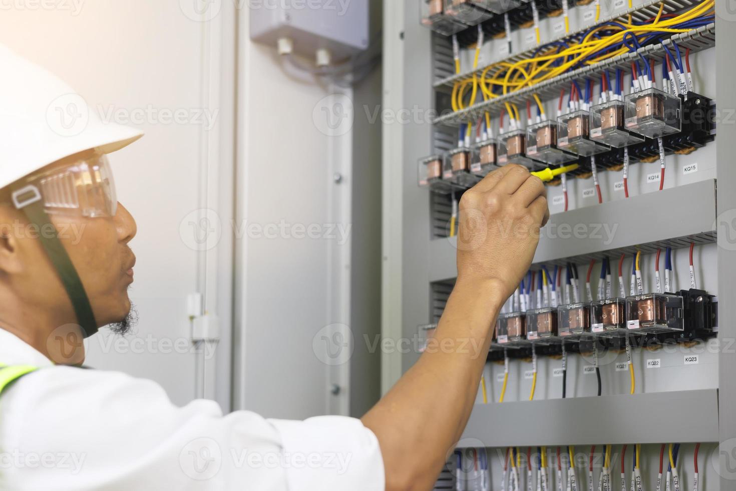 un electricista masculino trabaja en un panel de control con conexiones eléctricas que conectan dispositivos con una herramienta de concepto de trabajo compleja. foto