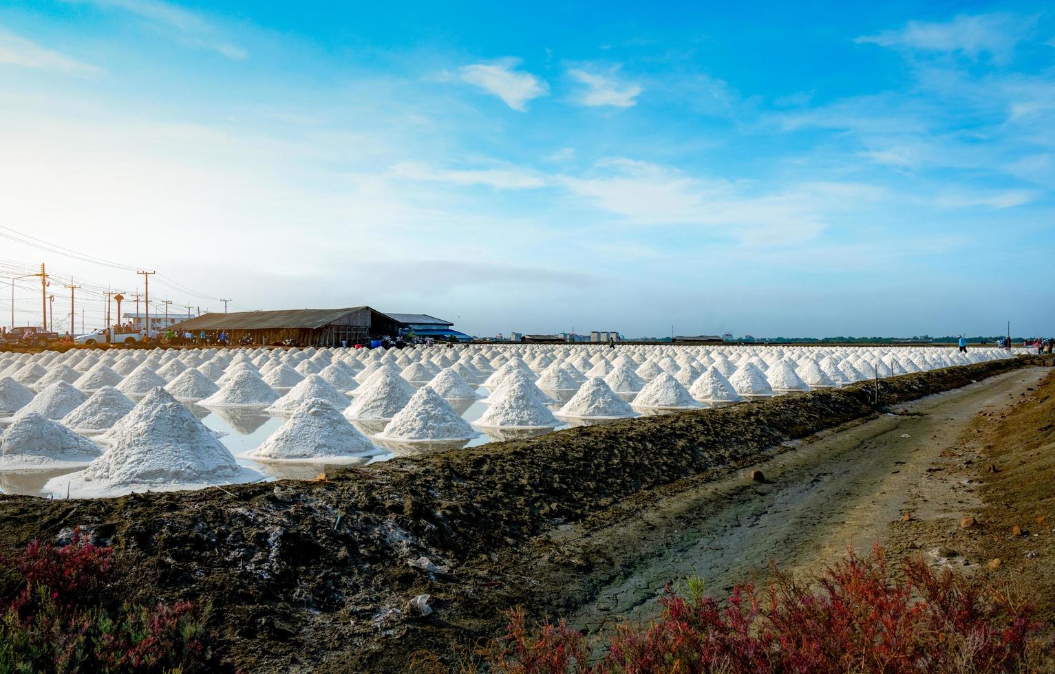 Sea salt farm and barn in Thailand. Organic sea salt. Raw material of salt industrial. Sodium Chloride. Solar evaporation system. Iodine source. Worker working in farm on sunny day with blue sky. photo