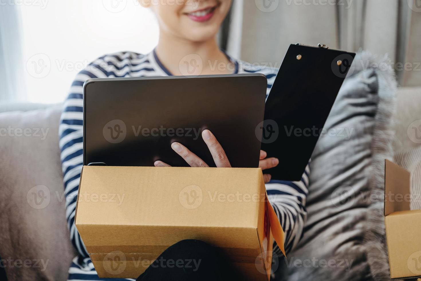 Online merchandising business idea, beautiful girl using ipad to check orders to deliver parcels to customers according to orders received from customers. photo