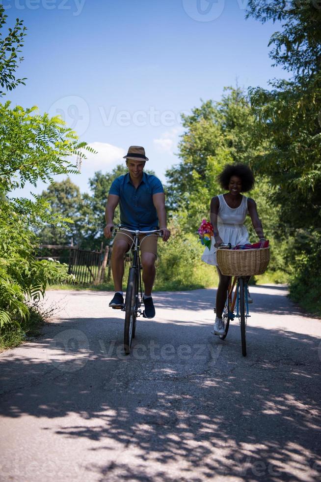 joven pareja multiétnica dando un paseo en bicicleta en la naturaleza foto