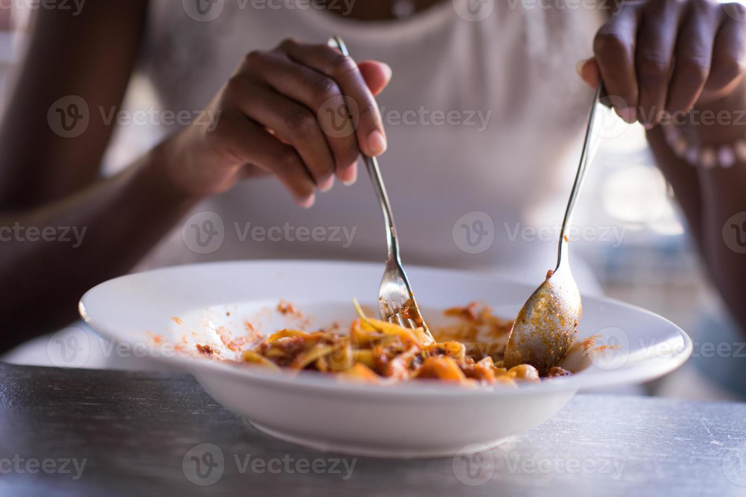 a young African American woman eating pasta photo