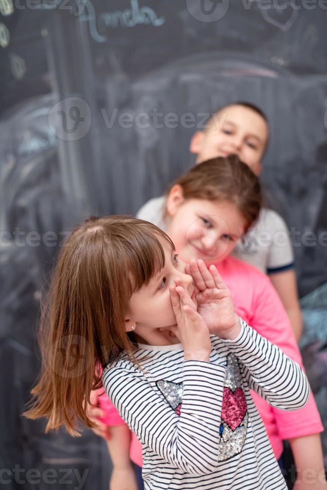 group of kids standing in front of chalkboard photo