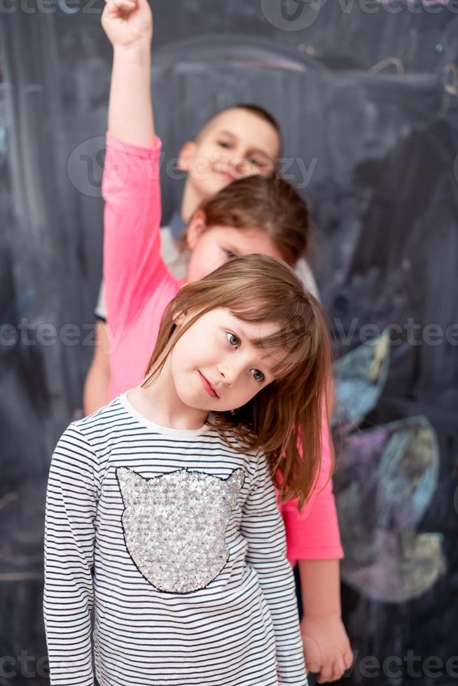 group of kids standing in front of chalkboard photo