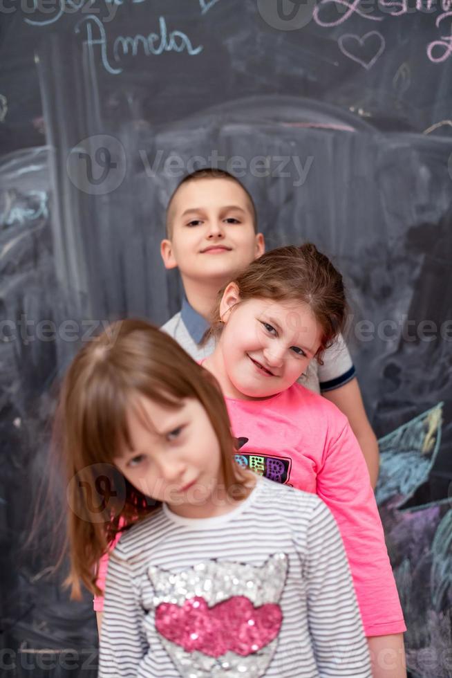 group of kids standing in front of chalkboard photo