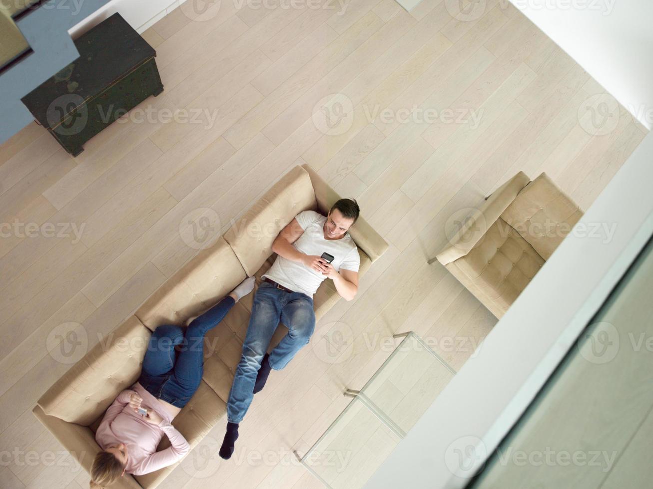 pareja en el sofá usando la vista superior de teléfonos móviles foto