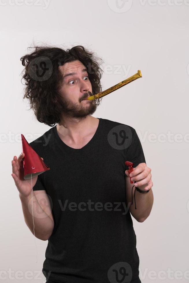 Portrait of a man in party hat blowing in whistle photo