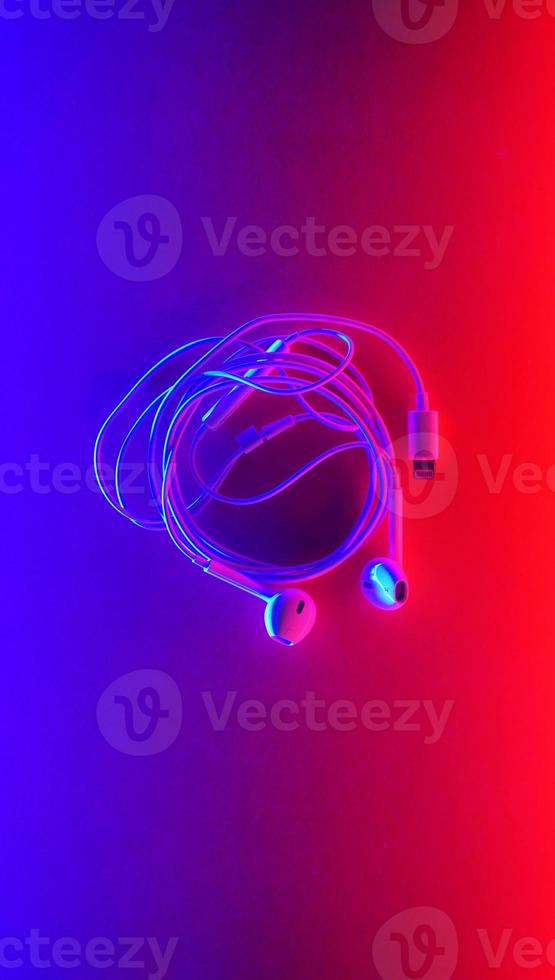Earphones, Earbud type white color and Cloud symbol made from cable isolated on blue and red gradient background, with copy space photo