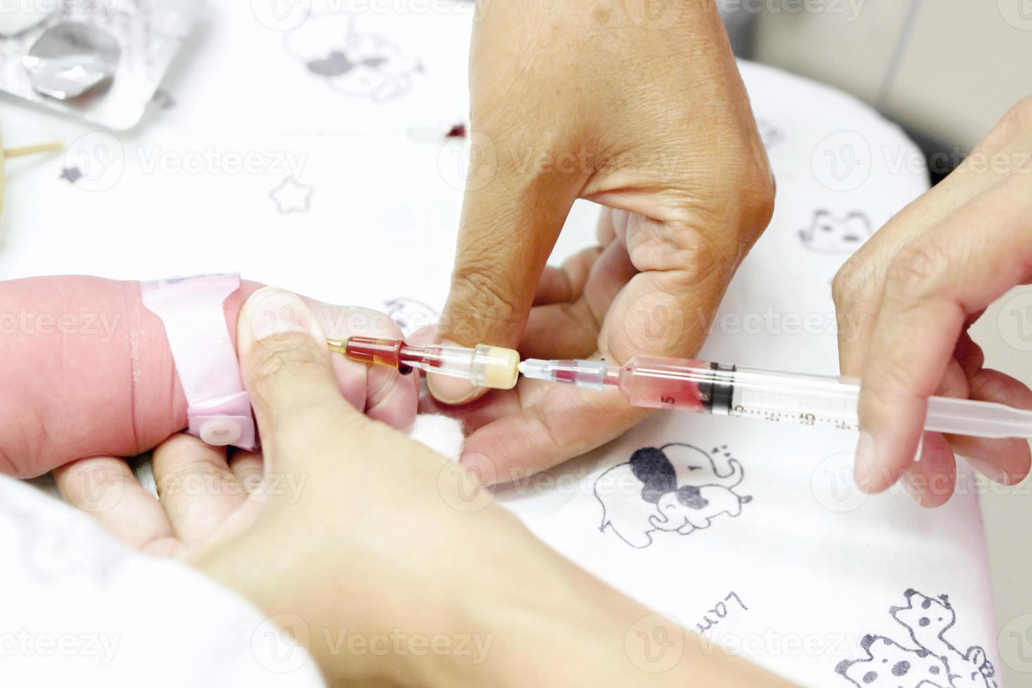 Image of a nurse hands is using a syringe gradually vaccinate on sick newborn baby's hand. photo