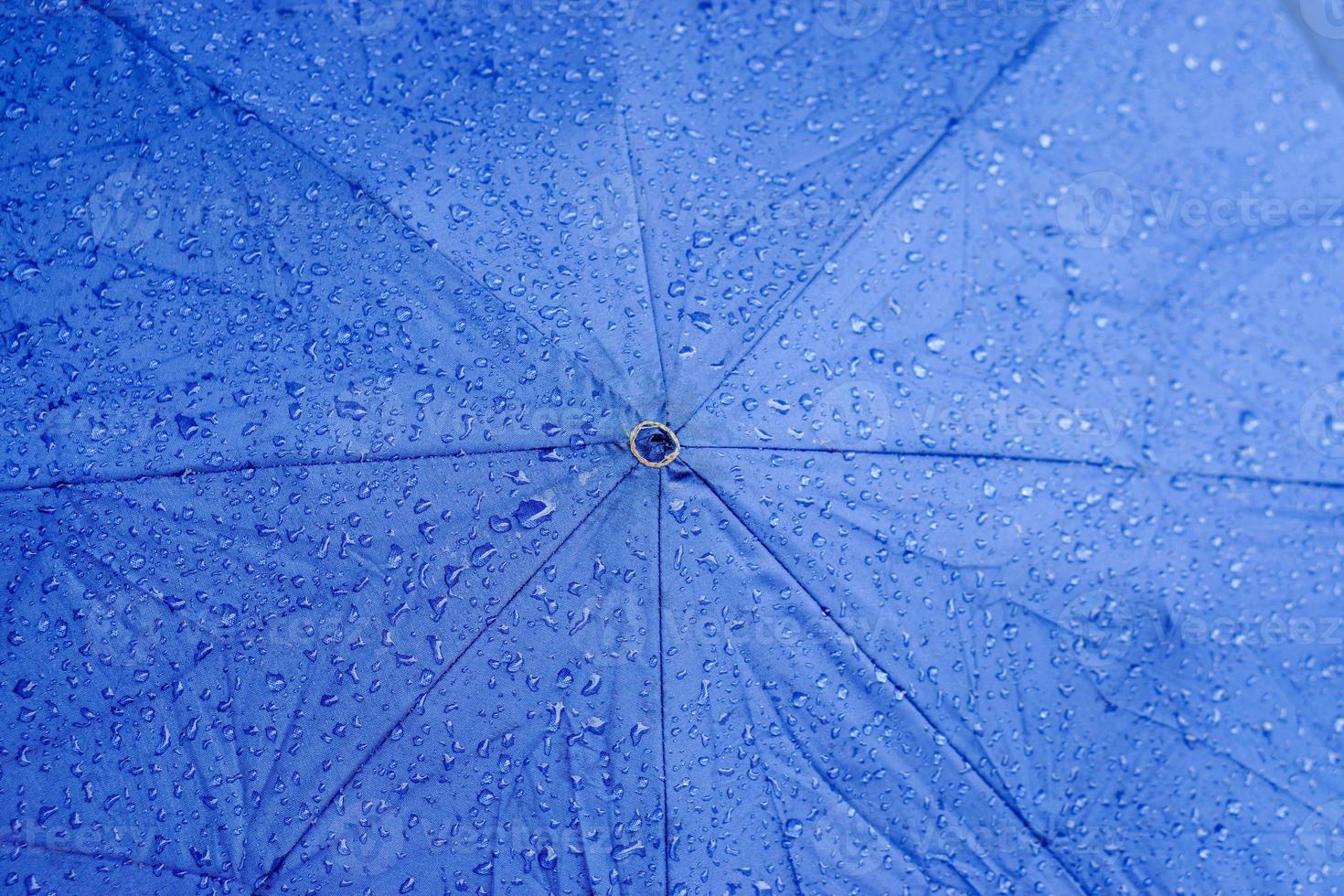 vista superior del fondo y la textura de las gotas de lluvia en el paraguas azul. foto