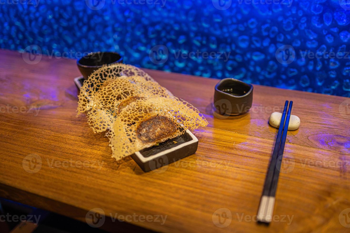 Fried dumplings Gyoza in a frying pan, soy sauce, and chopsticks on a brown wooden background, top view photo