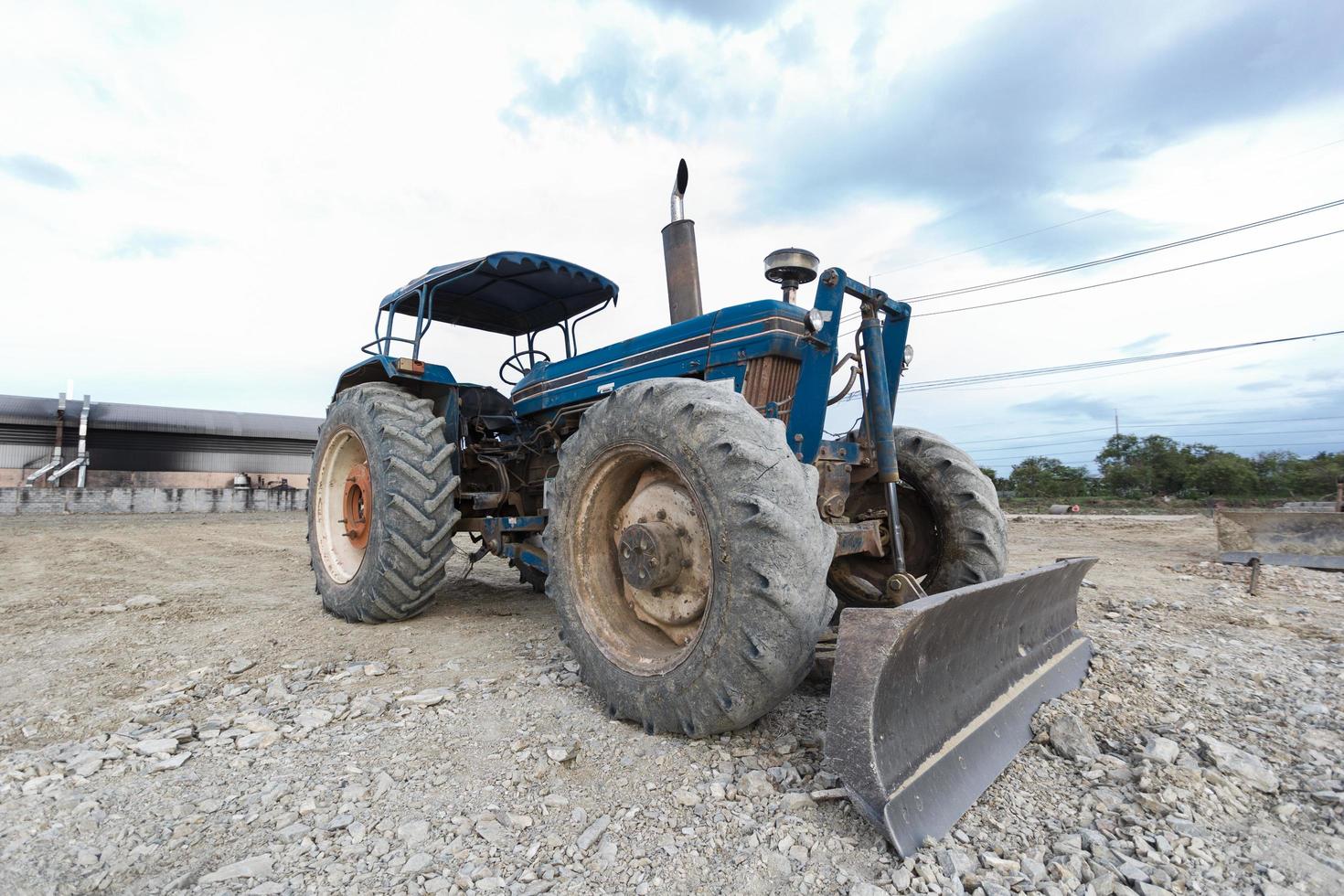 Tractor blue parked in a clearing in preparation for topsoil and beautiful blue sky in the background. The concept of a bulldozer prepares the topsoil for construction. photo