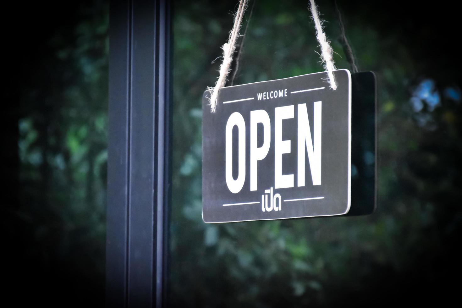 A shop label Open which hanging on the glass door of the shop, concept for informing people in Covid19 crisis situations around the world. photo