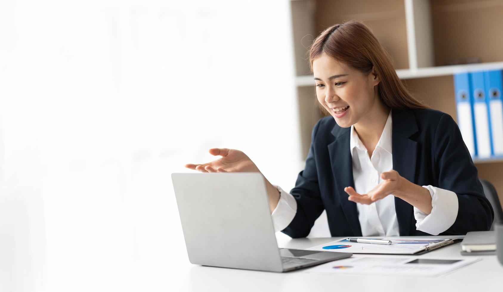 Young attractive business asian woman talking about sale report in video call conference on notebook computer online meeting in working from home. photo