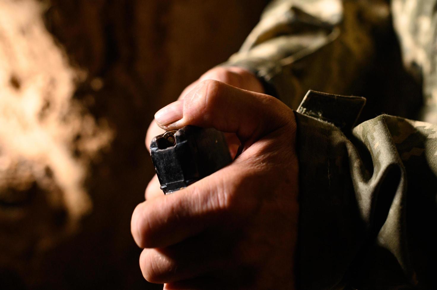 Filling the magazine with combat military assault rifles AK 74, a soldier in a trench holding ammunition for a machine gun. photo