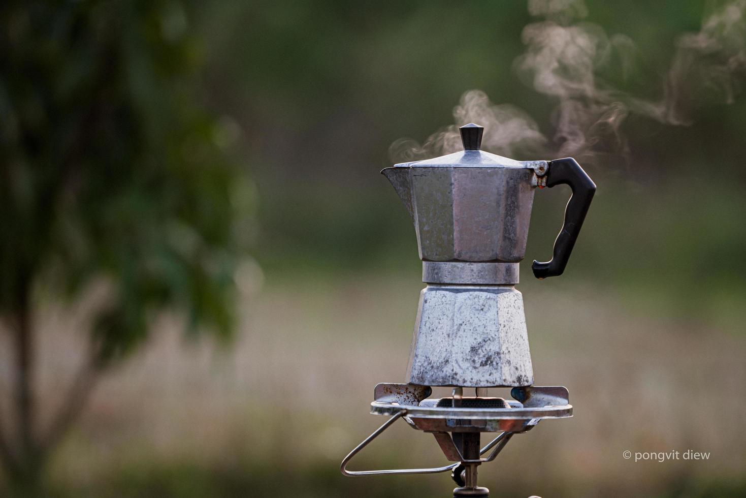 cafetera moka antigua en la estufa de gas para acampar cuando sale el sol por la mañana. enfoque suave. foto