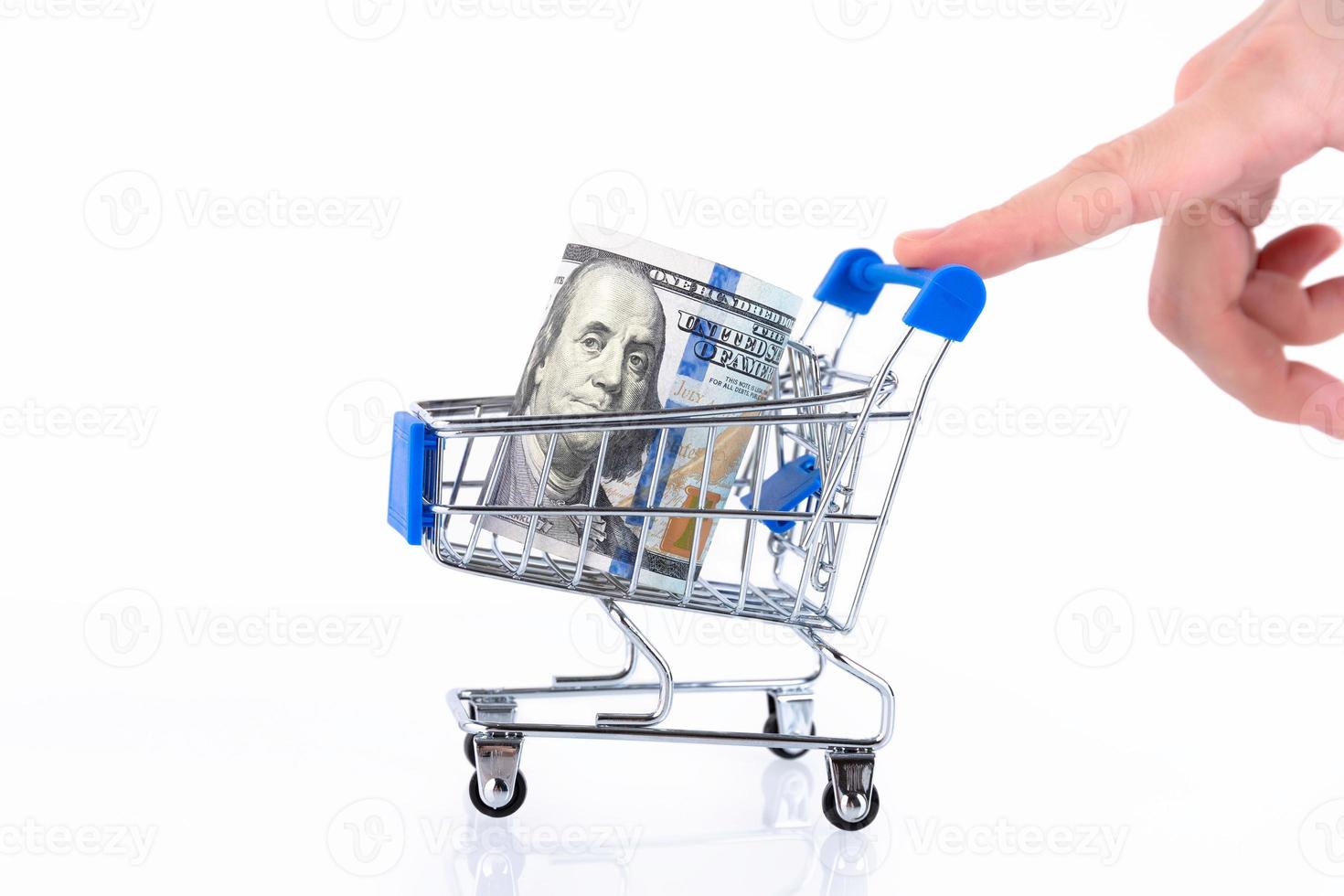A hand in the form of a walking man rolls up a shopping cart with a roll of one hundred dollar bills. Copy space. photo