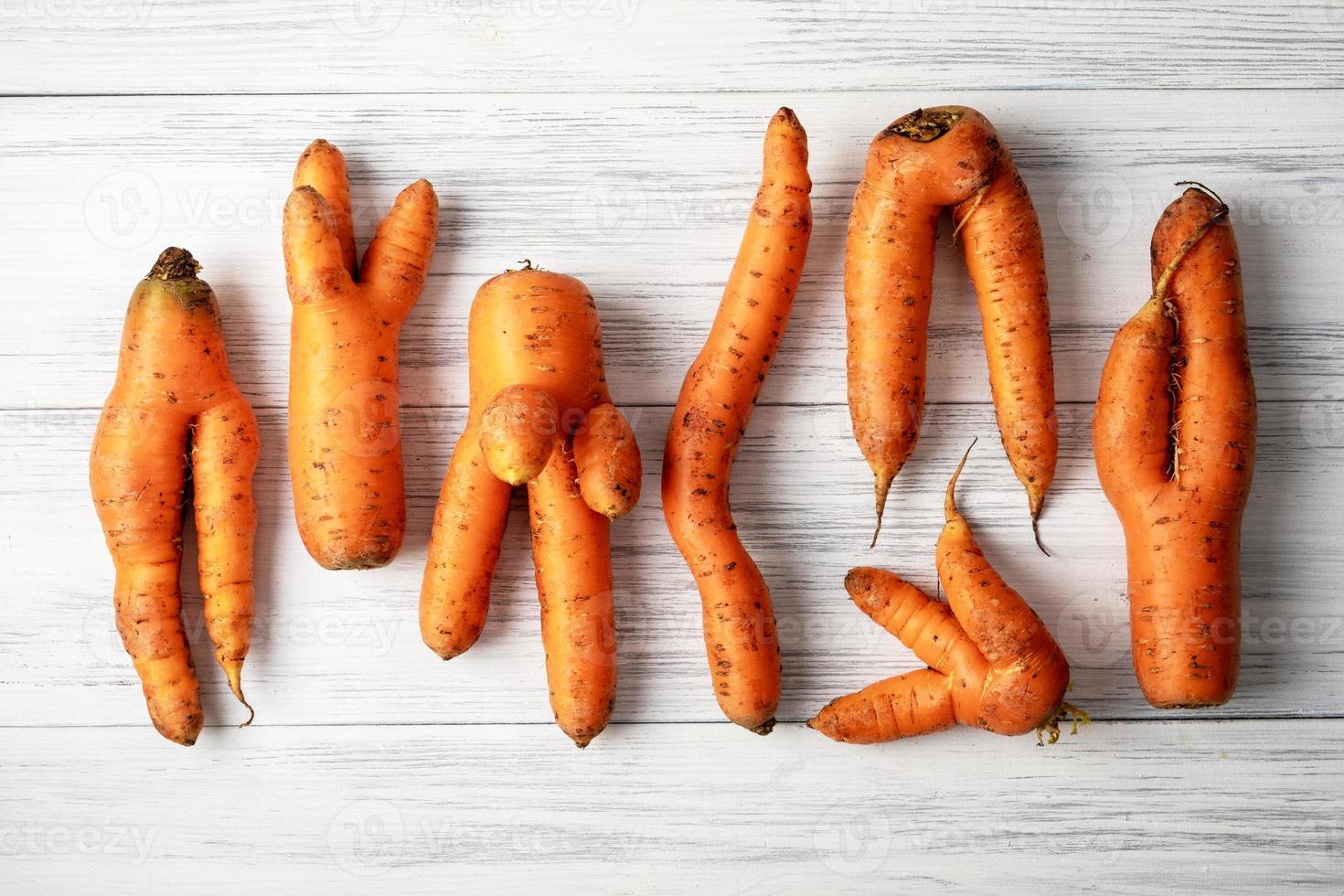 Ugly carrots lie on a light wooden surface photo