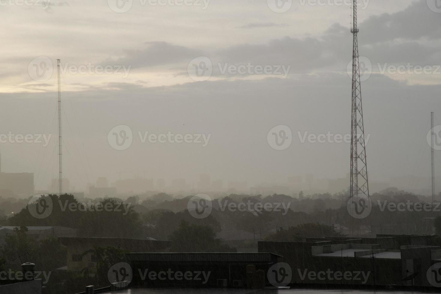 Background heavy rain falling from rainy season sky, tree and building silhouette, tropical Thailand. photo