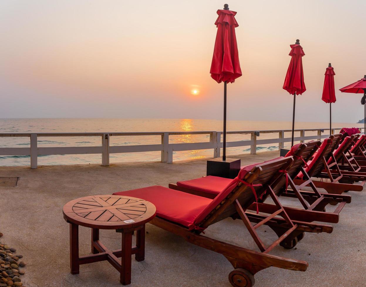 sombrilla roja y sillas de piscina al amanecer alrededor de la piscina al aire libre. foto