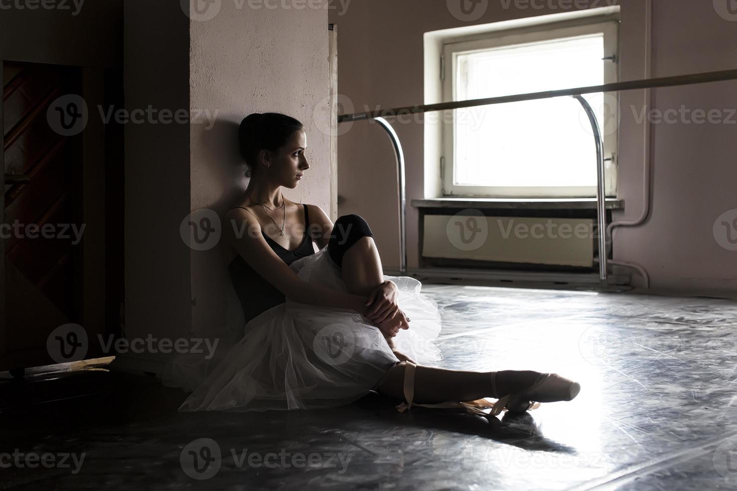 una bailarina encantadora en un traje de cuerpo posa elementos de ballet en un tocado en un estudio fotográfico foto