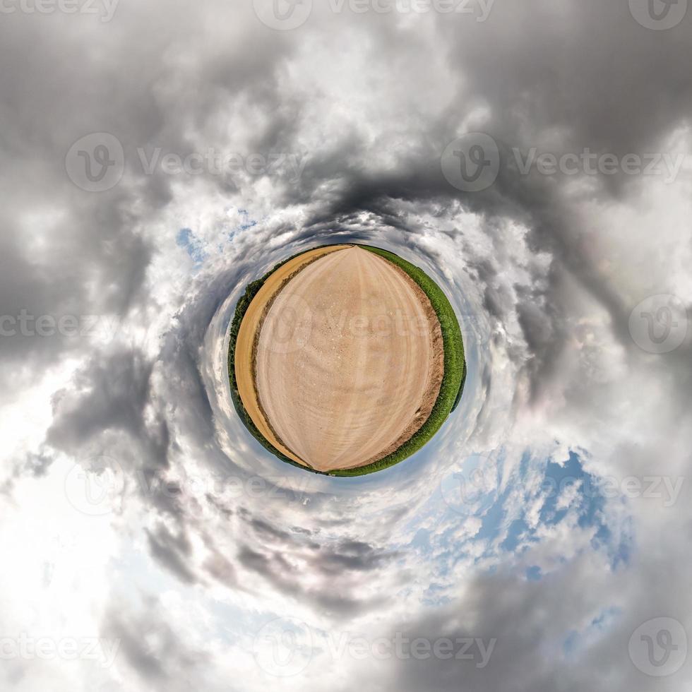 Little planet transformation of spherical panorama 360 degrees. Spherical abstract aerial view in field in nice evening with awesome beautiful clouds. Curvature of space. photo