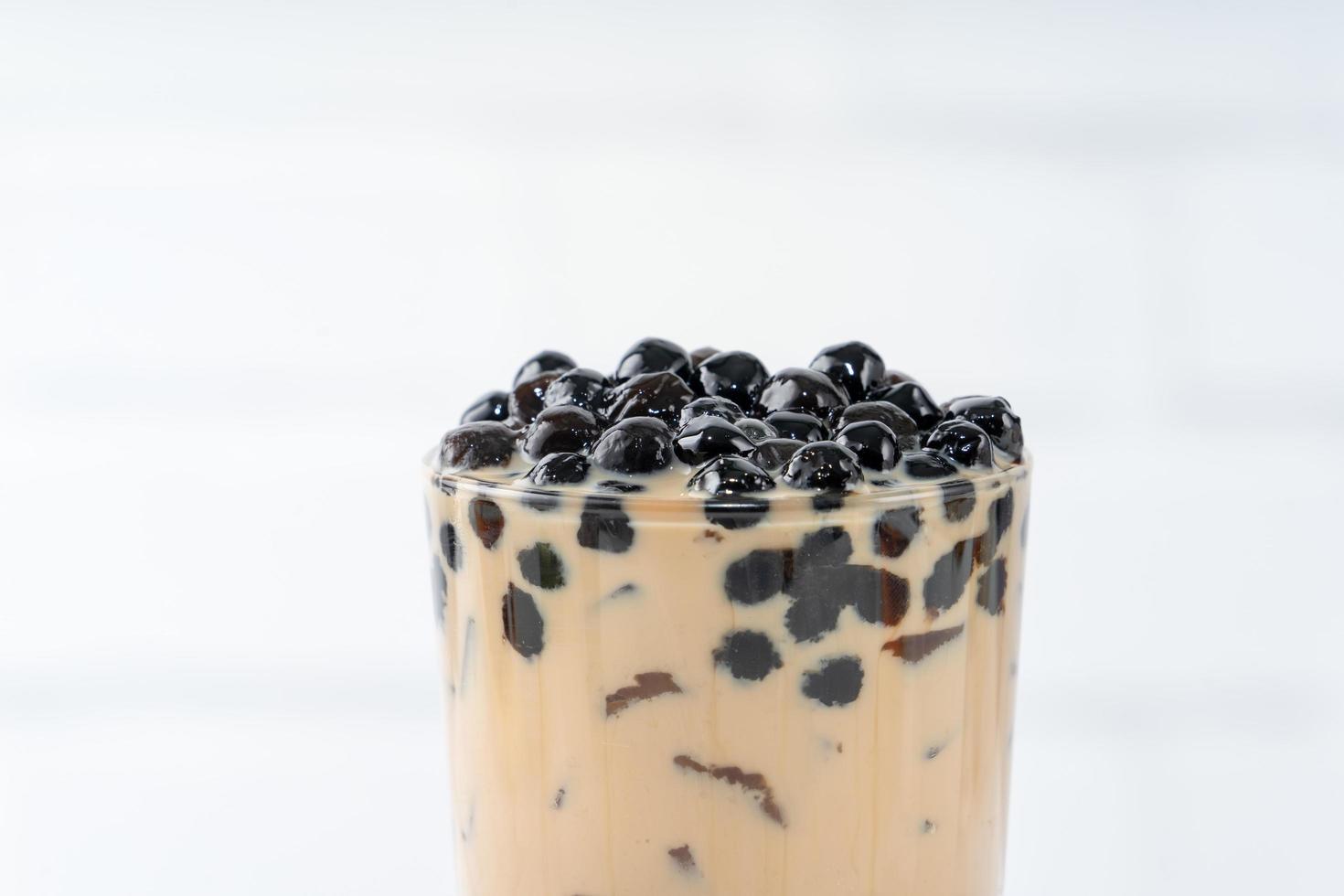 Bubble milk tea with tapioca pearl topping, famous Taiwanese drink on white wooden table background in drinking glass, close up, copy space photo