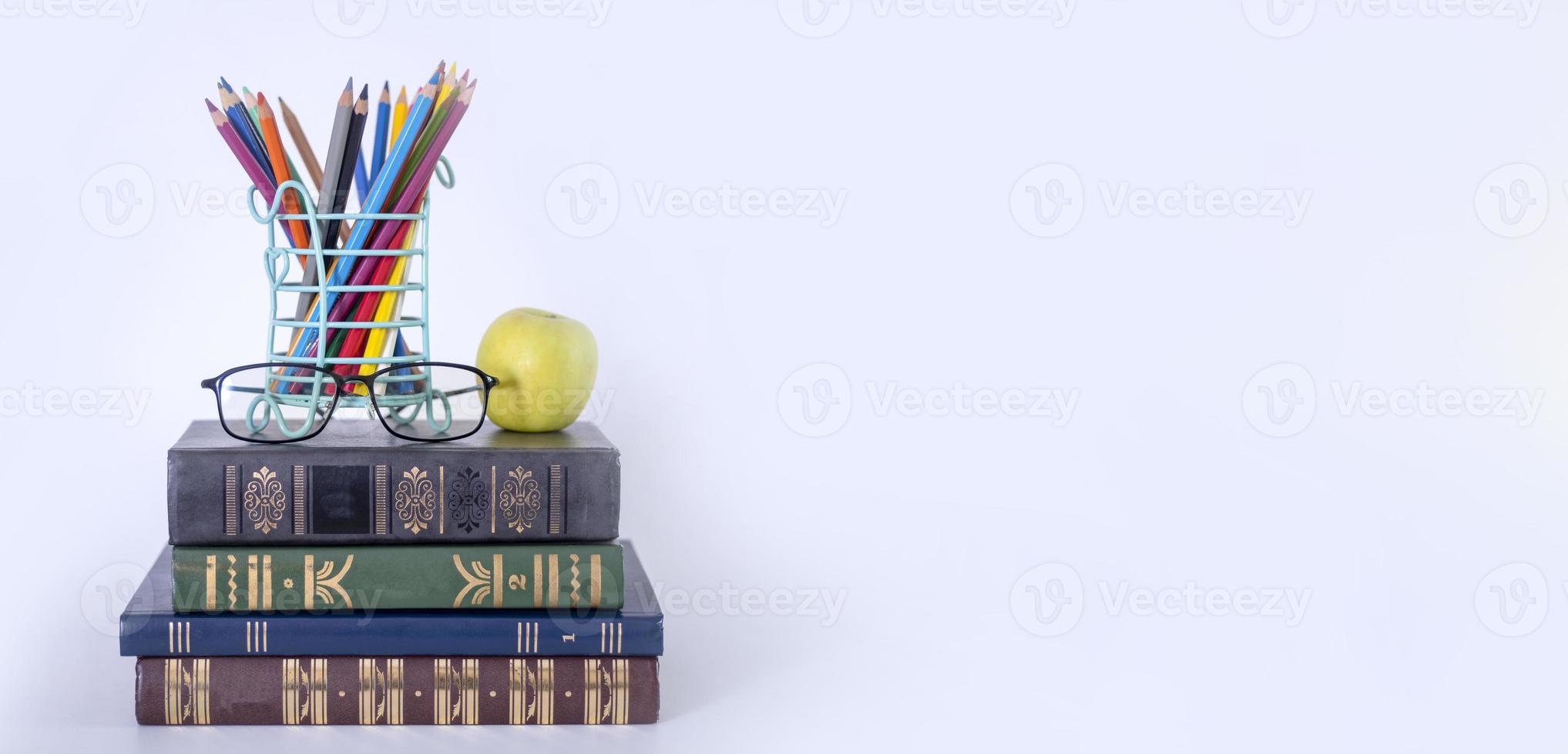A stack of books, study guides, textbooks, glasses, and pencils in a text copy holder. photo