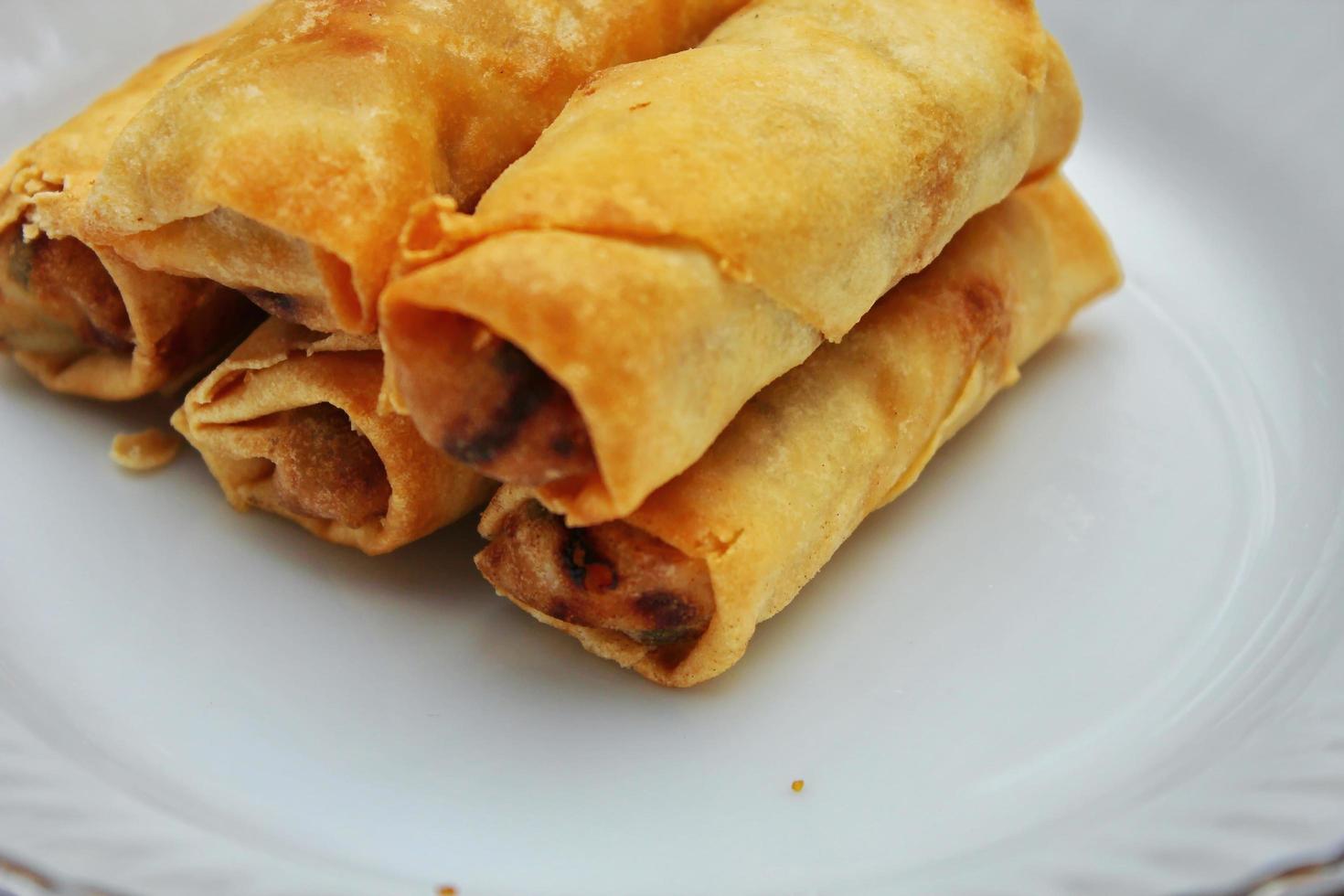 Fried spring rolls placed in a white plate, fried spring rolls are a popular Asian dish. photo