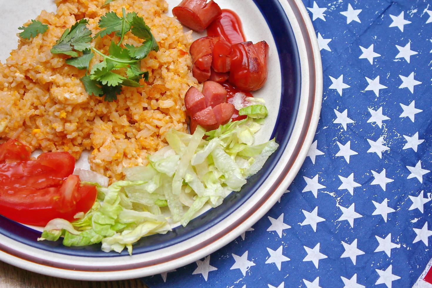 arroz frito con salchicha frita servido en un plato cremoso con tomates y pepinos. foto