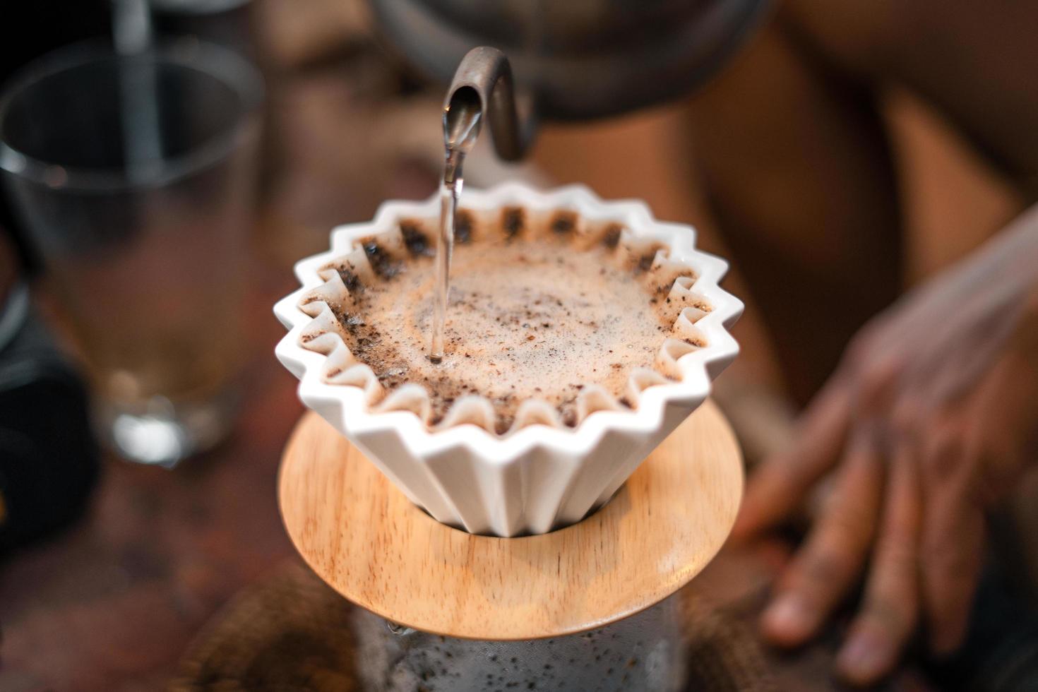 Drip coffee, barista pouring water on coffee ground with filter photo