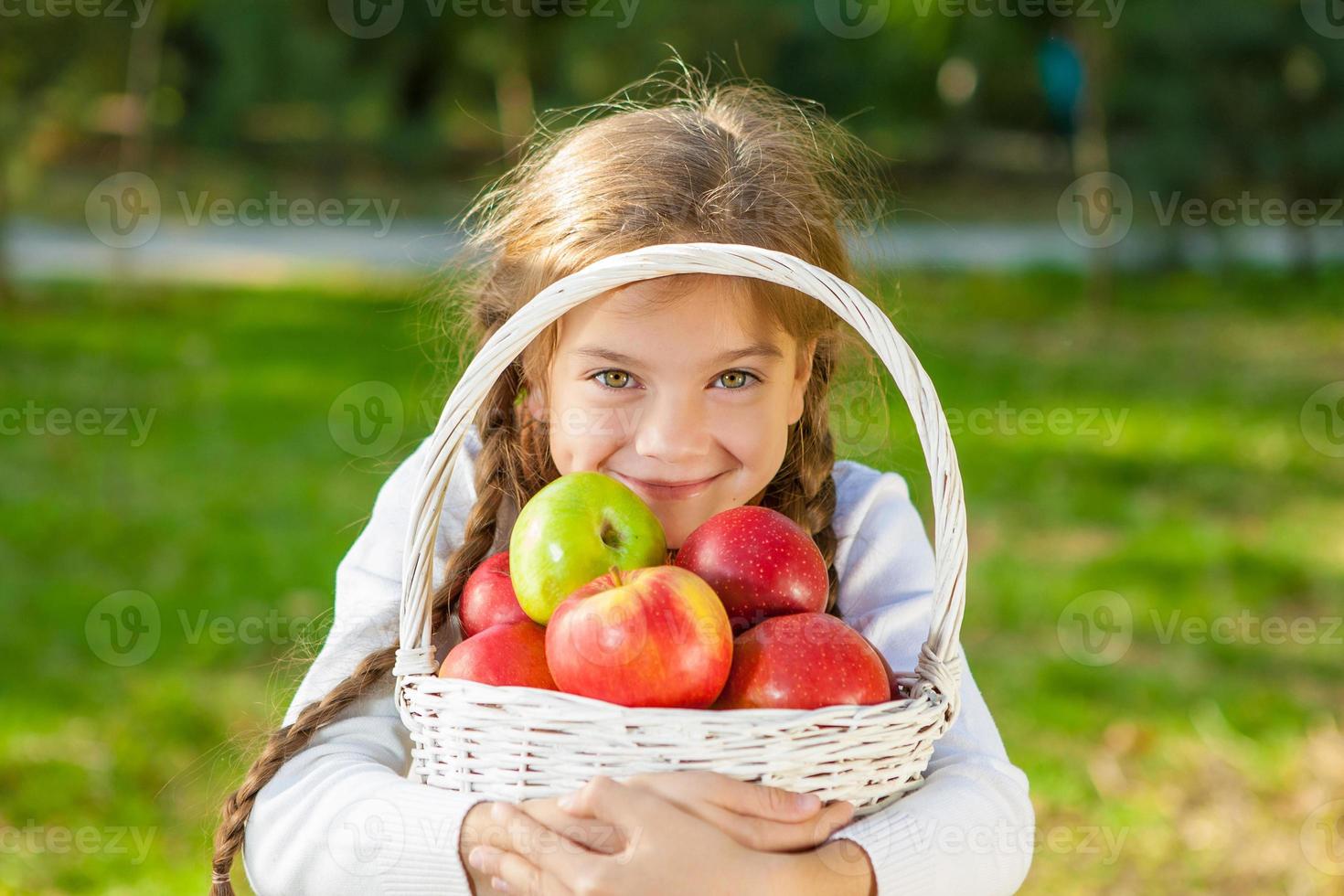 niña sosteniendo una cesta de manzanas foto