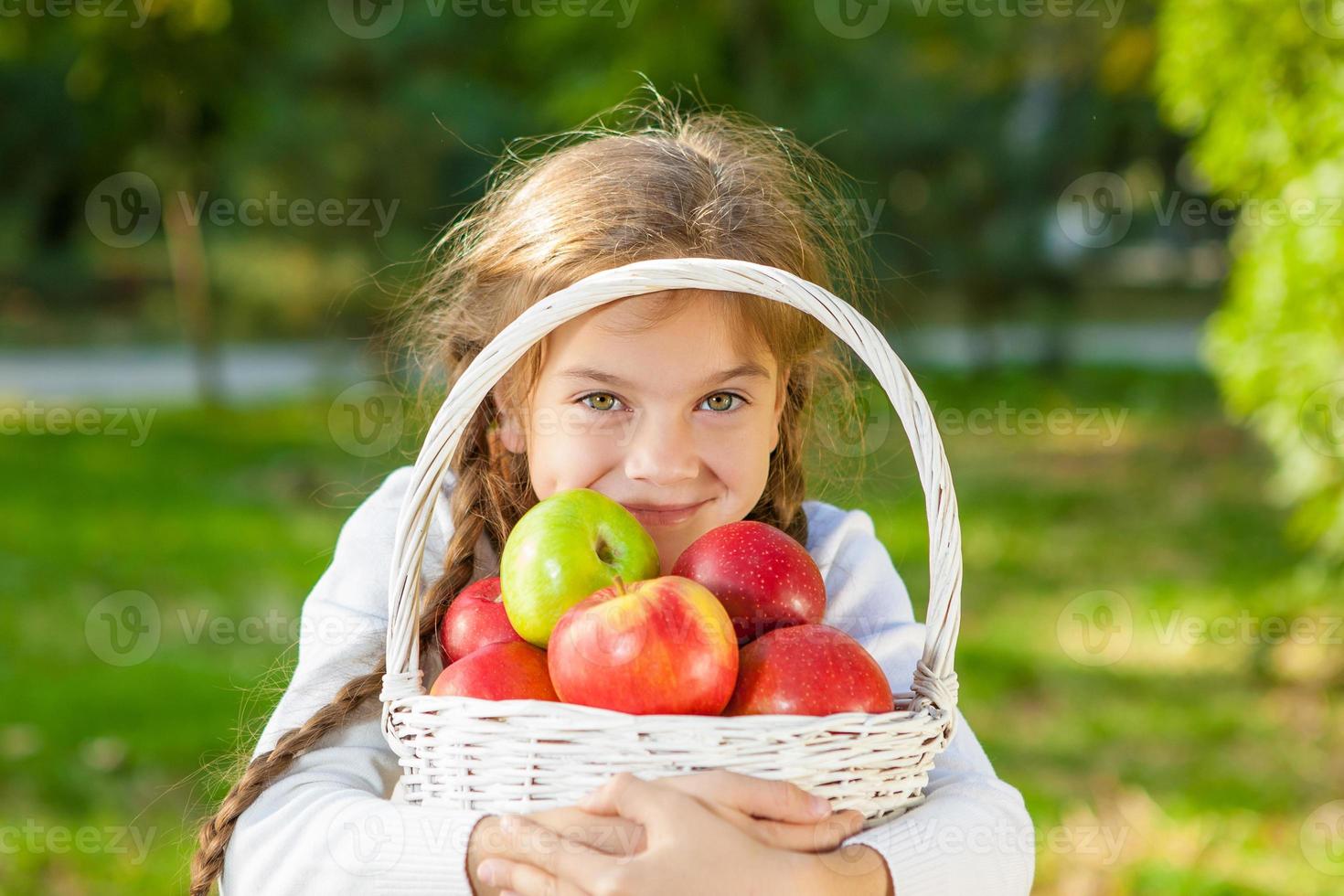 niña sosteniendo una cesta de manzanas foto