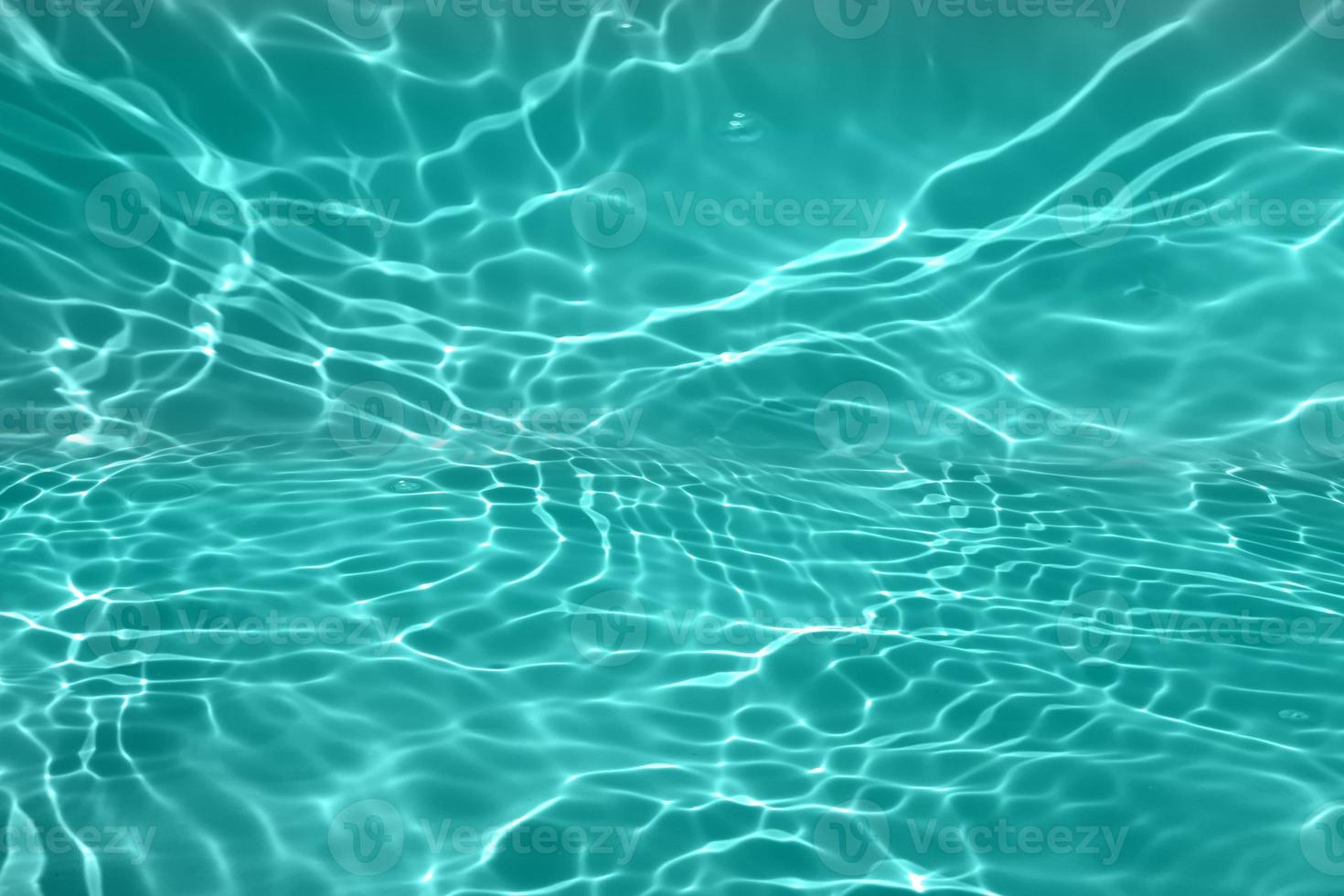 Defocus blurred transparent blue colored clear calm water surface texture with splashes and bubble. Trendy abstract nature background. Water wave in sunlight with copy space. Blue watercolor texture photo