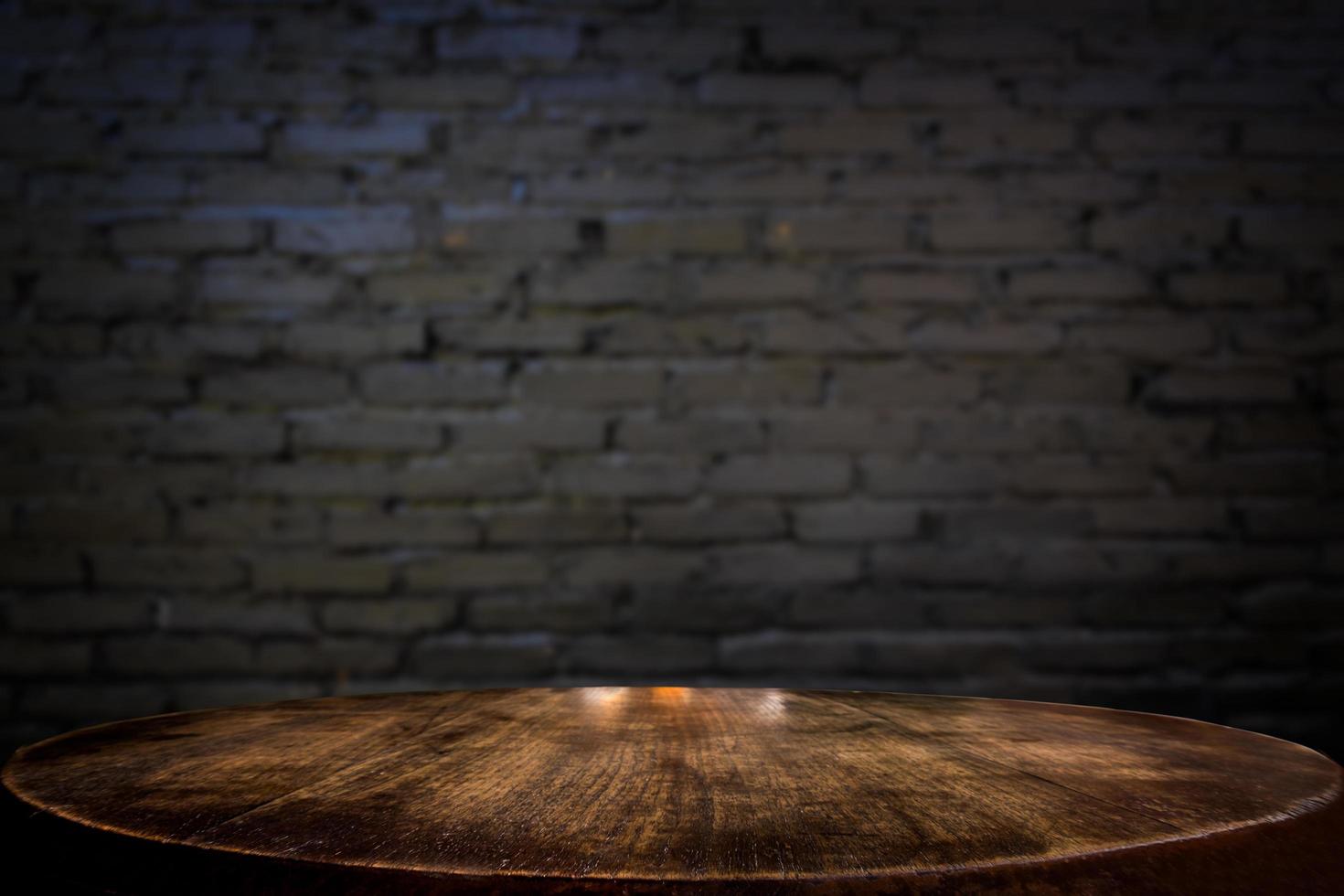 foco seleccionado mesa de madera marrón vacía y textura de pared o imagen de fondo de desenfoque de pared de ladrillo negro antiguo. para su fotomontaje o exhibición de productos foto