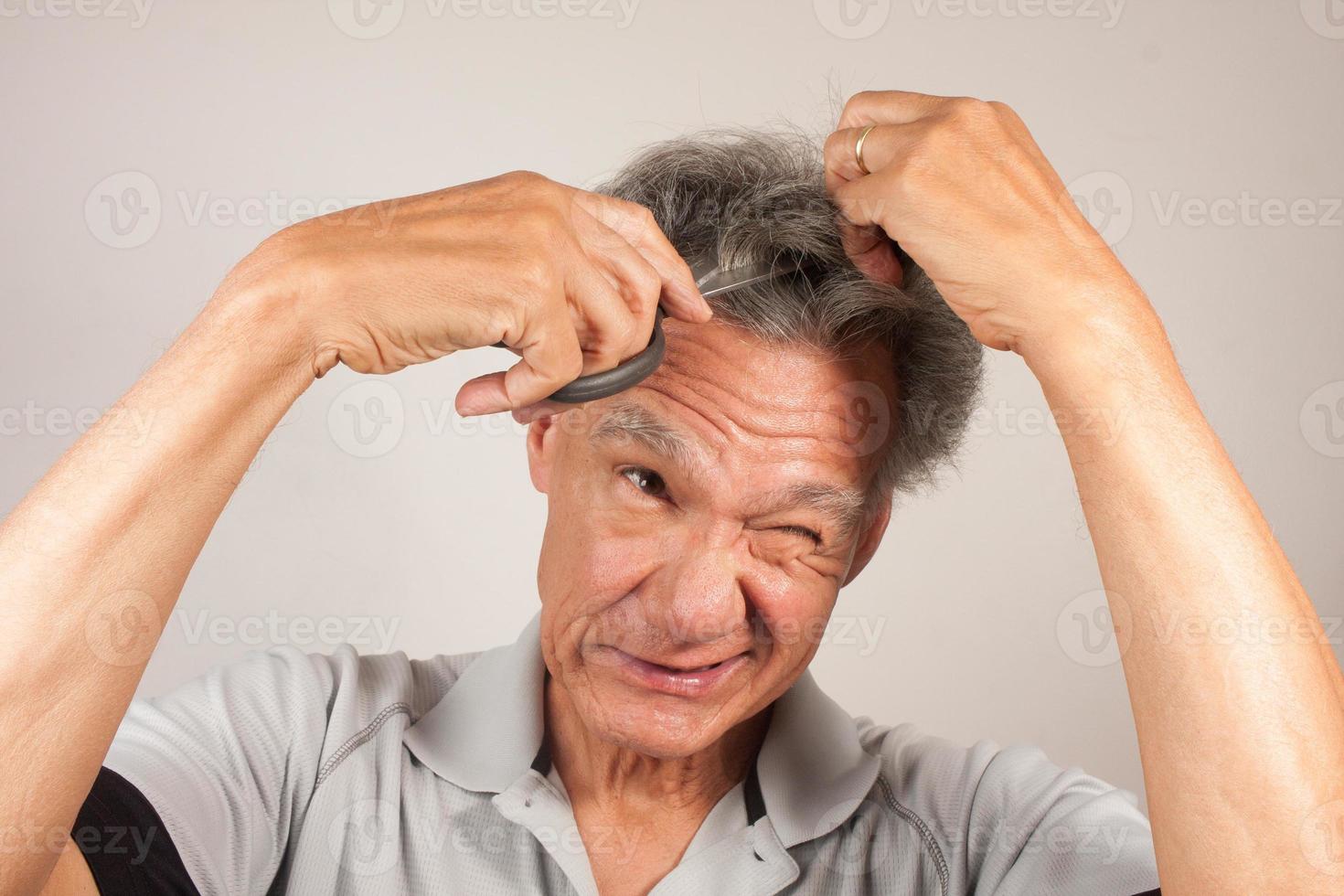 Mature Man trying to cut his own Hair with a Pair of Scissors photo