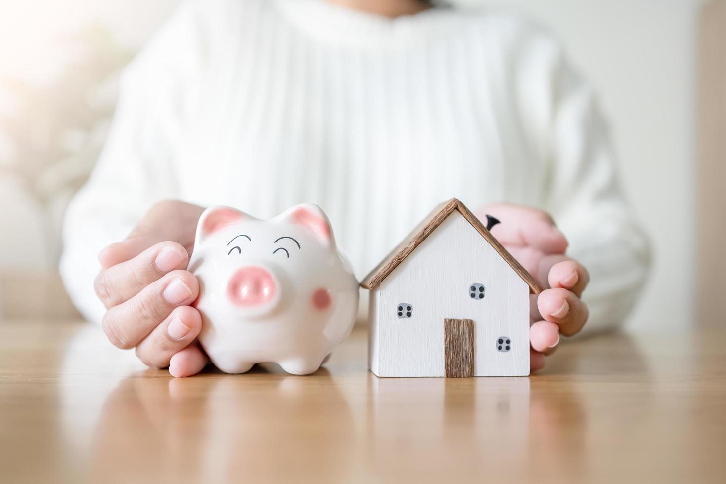 Woman with piggy bank and future house concept of saving and loan money for house. To rent or buy new house with saving money in piggy bank. photo